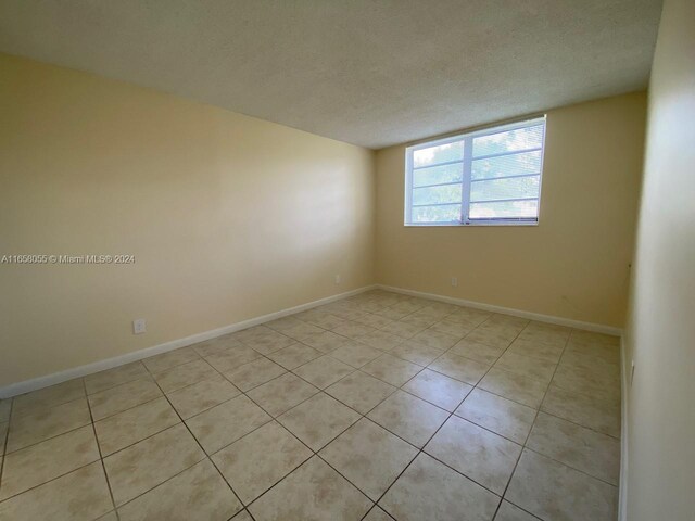 6071 NW 61st Ave Unit 107, Tamarac, FL 33319 - empty room with light tile patterned floors, a textured ceiling, and baseboards