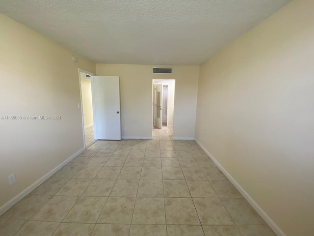 6071 NW 61st Ave Unit 107, Tamarac, FL 33319 - spare room with baseboards, light tile patterned floors, and a textured ceiling