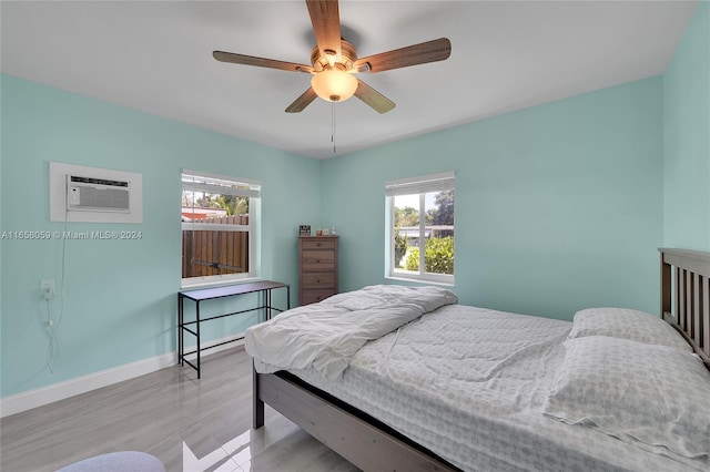 bedroom featuring ceiling fan, light hardwood / wood-style floors, multiple windows, and a wall unit AC