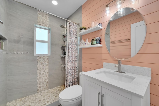 bathroom with vanity, wood walls, toilet, and curtained shower