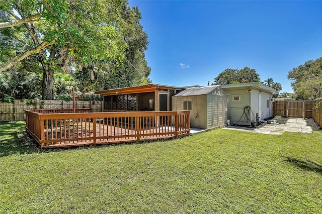 rear view of property with a yard, a wooden deck, and a storage unit