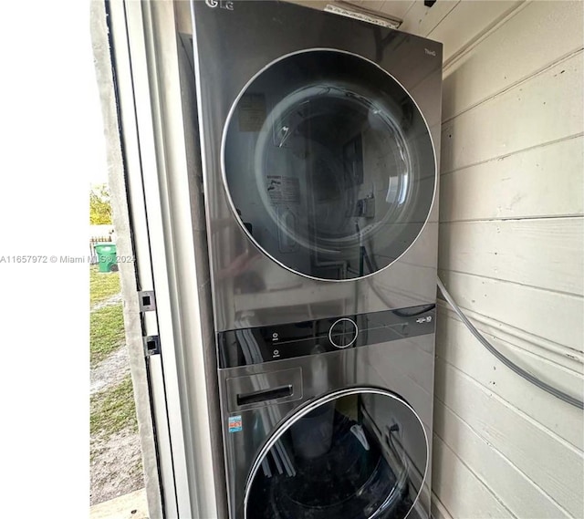 laundry room with wood walls and stacked washer and dryer