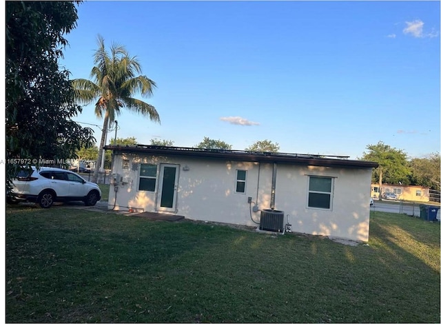 rear view of property with a lawn and central AC