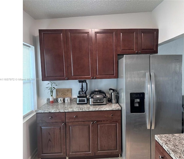 kitchen featuring stainless steel fridge with ice dispenser and a textured ceiling