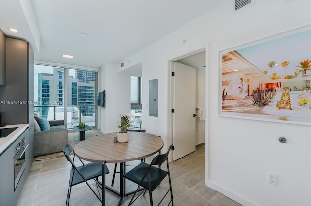 dining area featuring light tile patterned floors, electric panel, and floor to ceiling windows