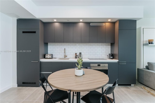 kitchen featuring sink, gray cabinetry, stainless steel oven, and decorative backsplash