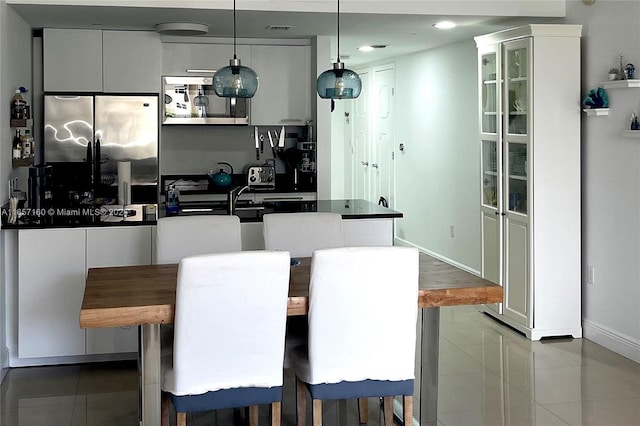 kitchen with hanging light fixtures, dark countertops, glass insert cabinets, and stainless steel appliances