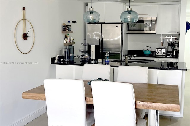 interior space with stainless steel appliances, dark countertops, hanging light fixtures, white cabinets, and modern cabinets