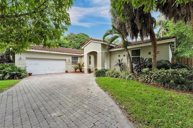 view of front of property with decorative driveway, a tile roof, an attached garage, and stucco siding