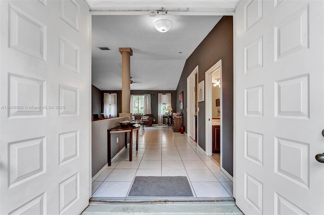 corridor featuring light tile patterned flooring, visible vents, baseboards, and ornate columns