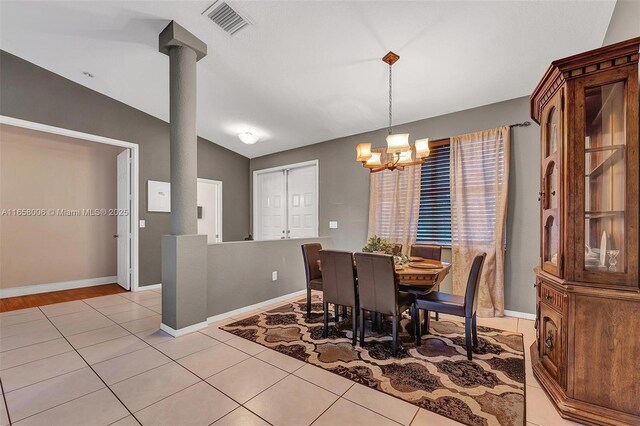 tiled dining room with lofted ceiling and an inviting chandelier