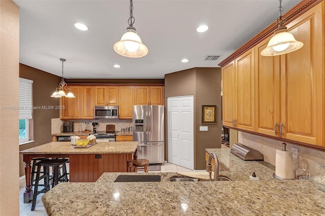 kitchen featuring a breakfast bar area, light stone countertops, visible vents, decorative backsplash, and appliances with stainless steel finishes