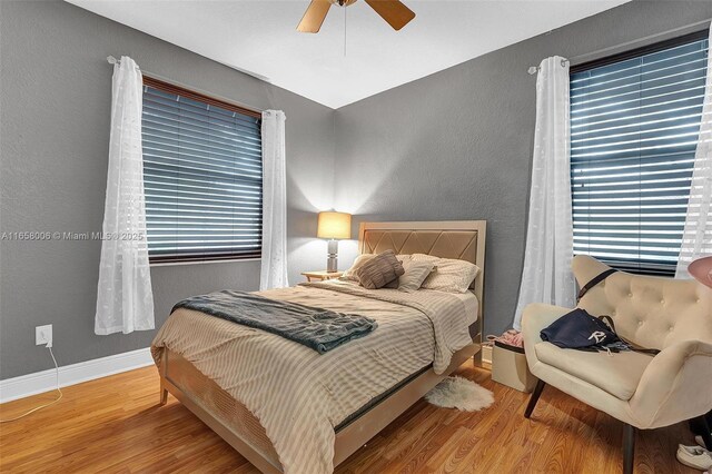 bedroom featuring multiple windows, ceiling fan, and hardwood / wood-style floors