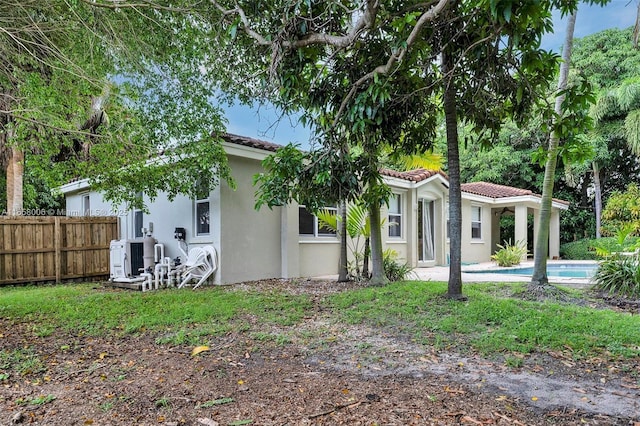 back of house featuring a fenced in pool, fence, central air condition unit, a tiled roof, and stucco siding