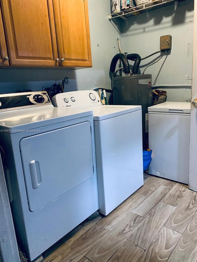 clothes washing area featuring separate washer and dryer, light hardwood / wood-style flooring, and cabinets