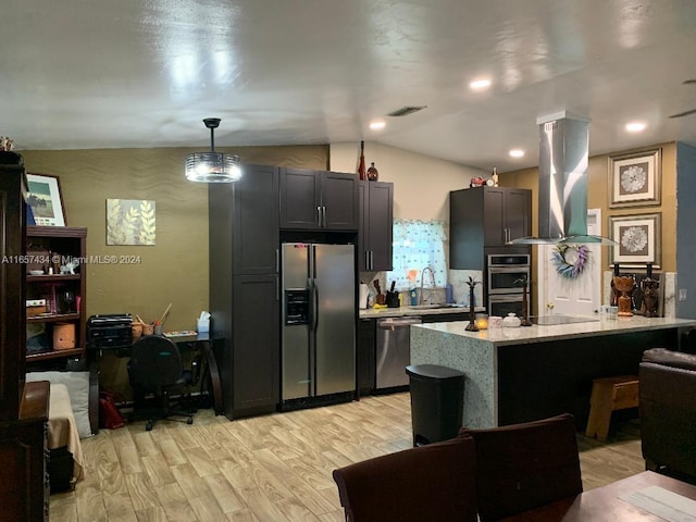 kitchen with island exhaust hood, decorative light fixtures, vaulted ceiling, appliances with stainless steel finishes, and light hardwood / wood-style floors