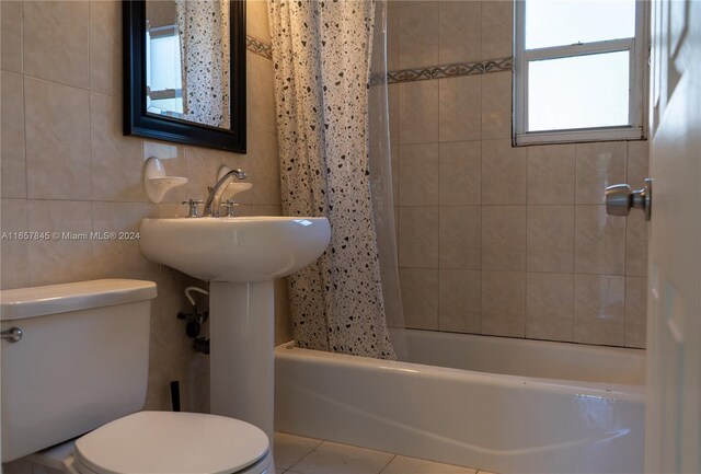 bathroom with tile patterned flooring, shower / bath combination with curtain, tile walls, and toilet