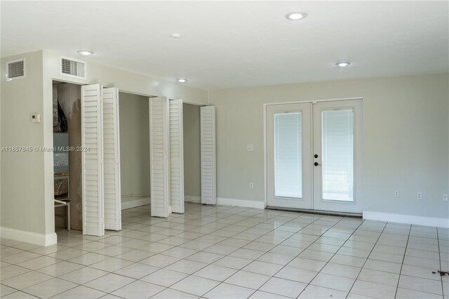 tiled empty room featuring french doors