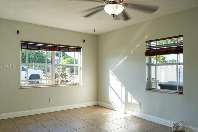 tiled spare room featuring a wealth of natural light, ceiling fan, and a textured ceiling