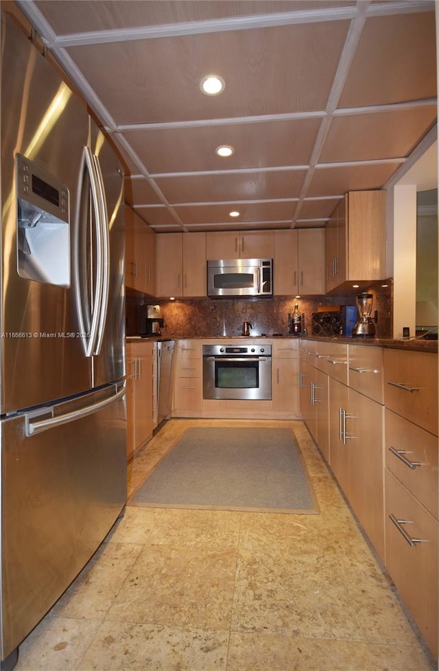 kitchen with appliances with stainless steel finishes, light brown cabinetry, and backsplash