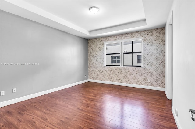 unfurnished room featuring a tray ceiling and dark hardwood / wood-style flooring