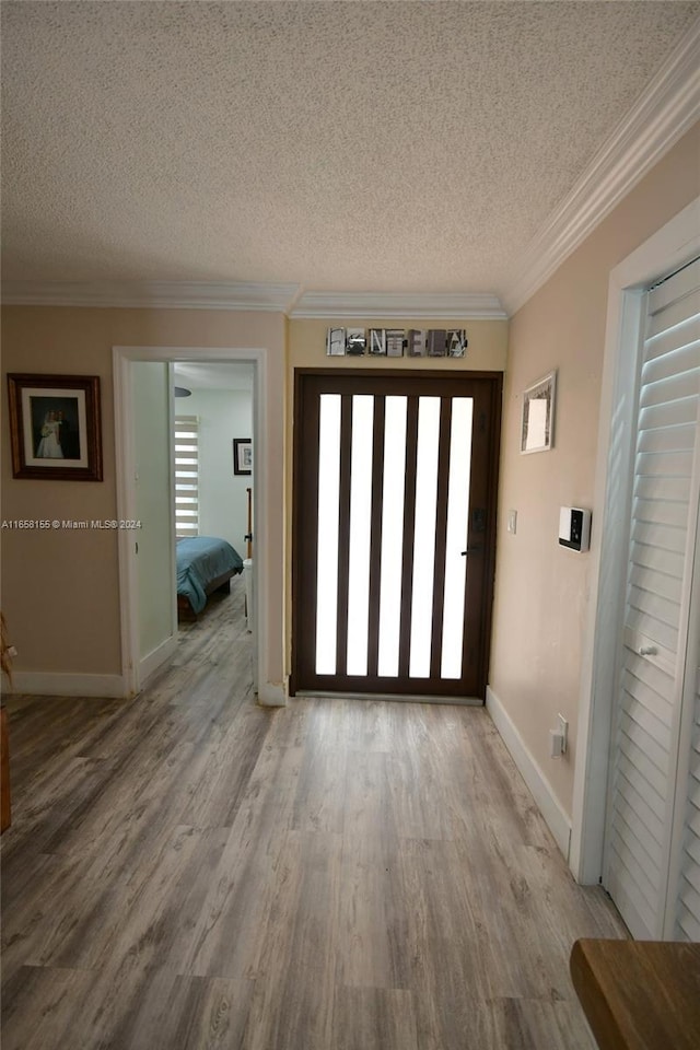 foyer entrance featuring crown molding, a textured ceiling, wood finished floors, and baseboards
