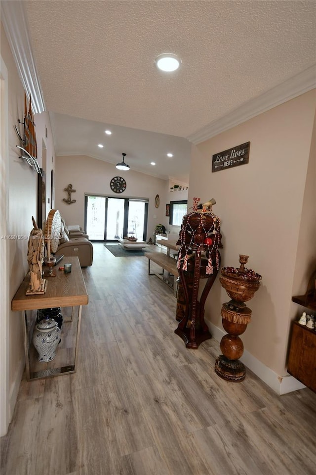 hall with lofted ceiling, recessed lighting, a textured ceiling, crown molding, and wood finished floors