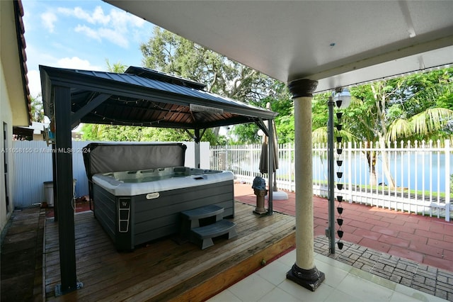 wooden deck featuring a water view, a gazebo, a hot tub, and a fenced backyard