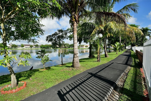 surrounding community with a water view, a yard, and fence