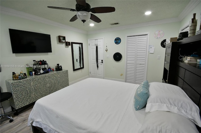 bedroom with ceiling fan, light hardwood / wood-style floors, a textured ceiling, and ornamental molding