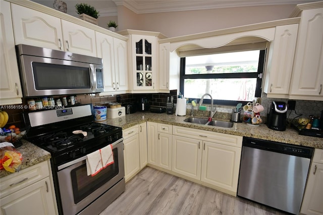 kitchen with crown molding, appliances with stainless steel finishes, tasteful backsplash, and a sink