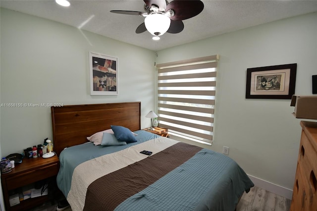 bedroom with a textured ceiling, light hardwood / wood-style flooring, and ceiling fan