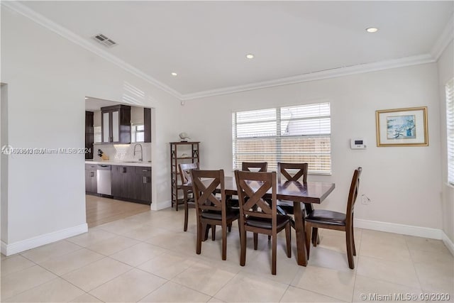 dining room with vaulted ceiling, sink, light tile patterned flooring, and ornamental molding