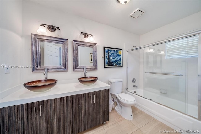 full bathroom with tile patterned floors, shower / bath combination with glass door, toilet, and vanity