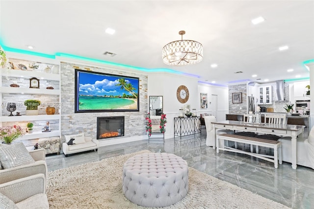 living room with crown molding, a notable chandelier, and a fireplace