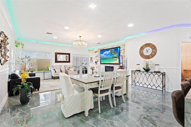 dining space featuring ornamental molding, a chandelier, and a fireplace