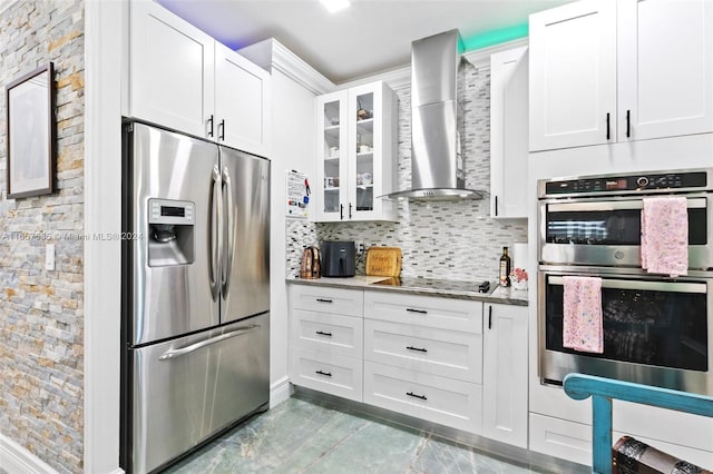 kitchen with white cabinetry, light stone countertops, stainless steel appliances, and wall chimney exhaust hood