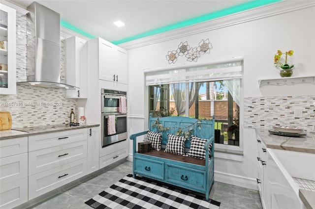 kitchen with wall chimney exhaust hood, black electric stovetop, and white cabinetry