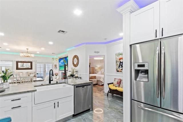 kitchen featuring light stone countertops, appliances with stainless steel finishes, sink, white cabinets, and ornamental molding