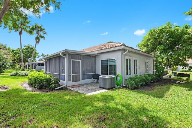 rear view of property with cooling unit, a yard, and a sunroom