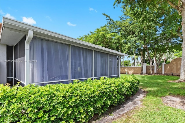 view of property exterior featuring a sunroom and a lawn