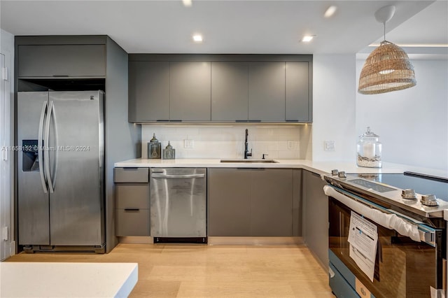 kitchen with tasteful backsplash, light hardwood / wood-style flooring, sink, gray cabinets, and stainless steel appliances