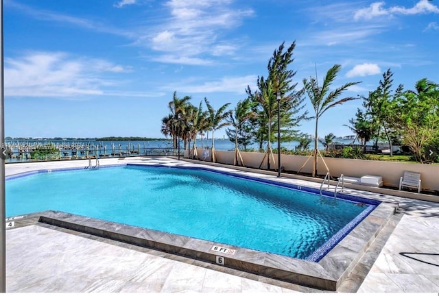 view of swimming pool with a patio area and a water view