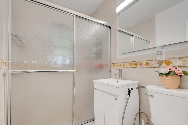 bathroom featuring vanity, toilet, an enclosed shower, and tile walls