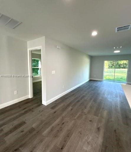 unfurnished living room featuring plenty of natural light and dark wood-type flooring