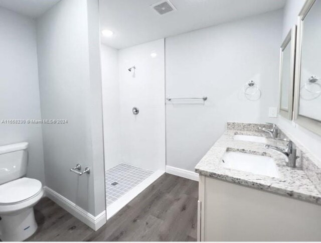 bathroom featuring a shower, hardwood / wood-style floors, toilet, and vanity