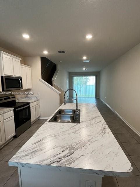 kitchen with a center island with sink, sink, appliances with stainless steel finishes, and white cabinetry