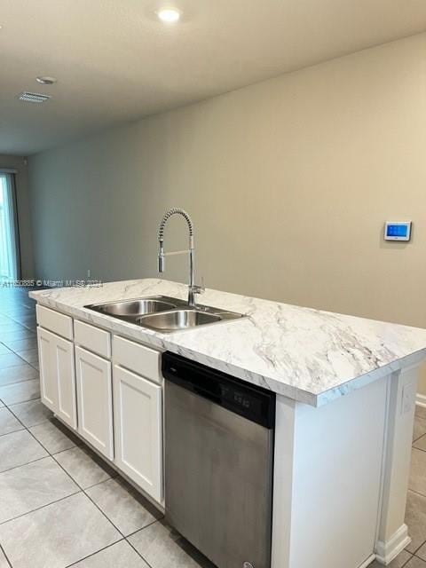 kitchen featuring light tile patterned floors, a kitchen island with sink, stainless steel dishwasher, sink, and white cabinets