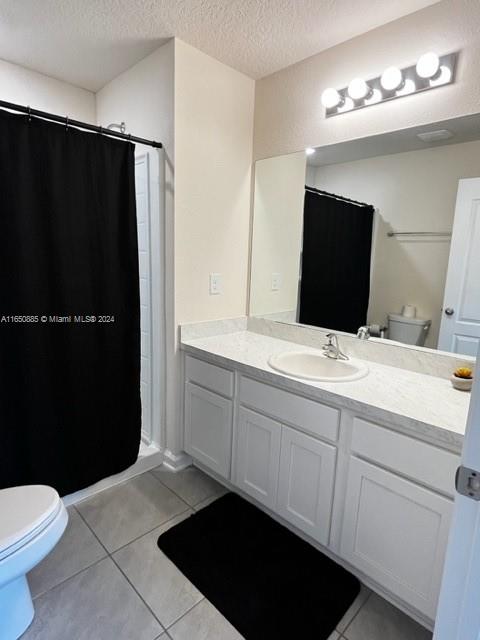 bathroom with walk in shower, toilet, a textured ceiling, and vanity