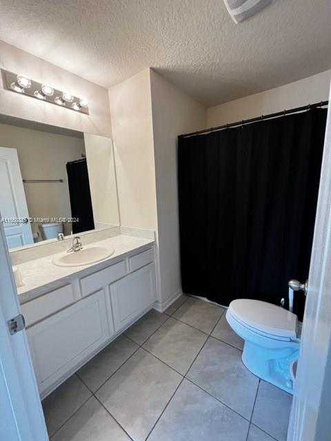 bathroom featuring tile patterned floors, toilet, a textured ceiling, and vanity